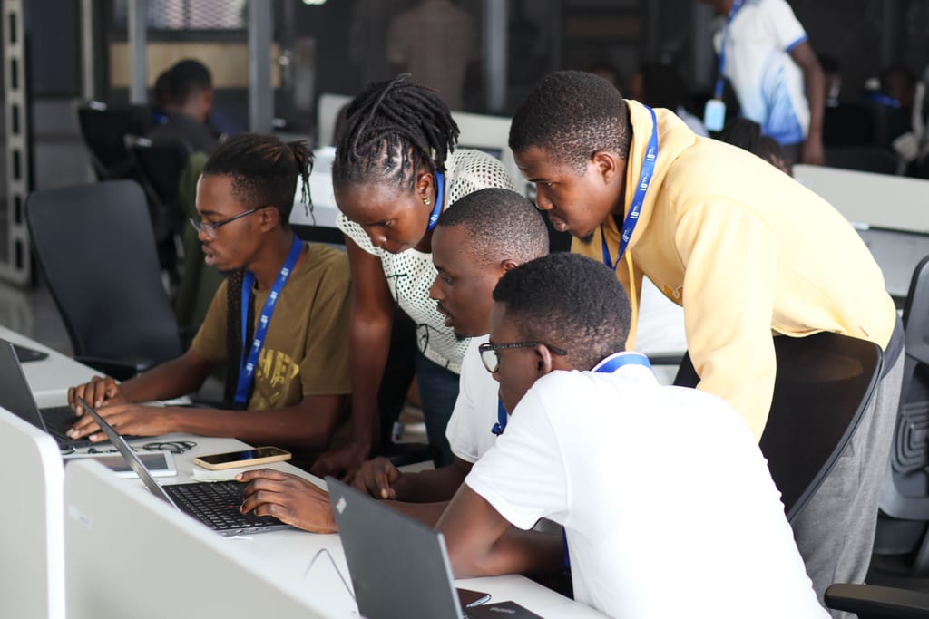 Students gathered around laptops during a coding workshop